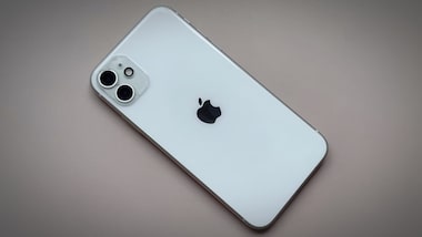 alt="Traseira do iPhone 11 na cor branca apoiado sobre uma superfície lisa, destacando o logotipo da Apple e o módulo duplo de câmeras."